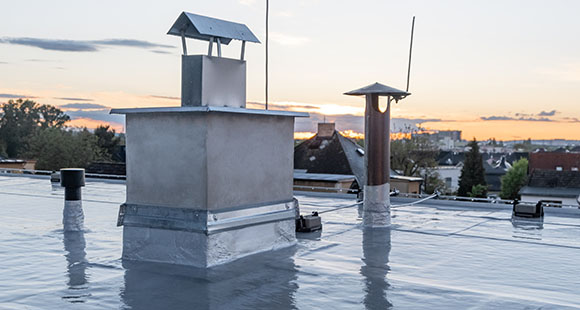 a rubber flat roof with chimneys in a suburban environment