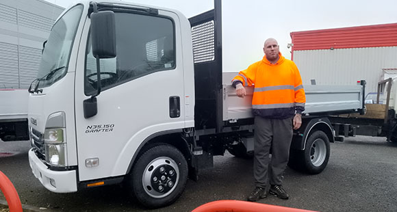 a man posing next to a pickup truck for carrying flat roof materials